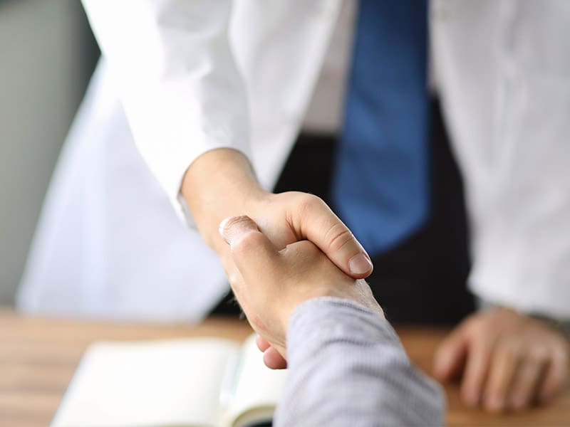 Closeup image of healthcare professional or doctor or dentist shaking hands with patient.